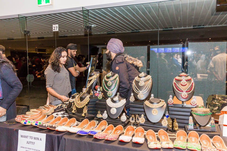 A group of people are standing around a table with jewelry on it.