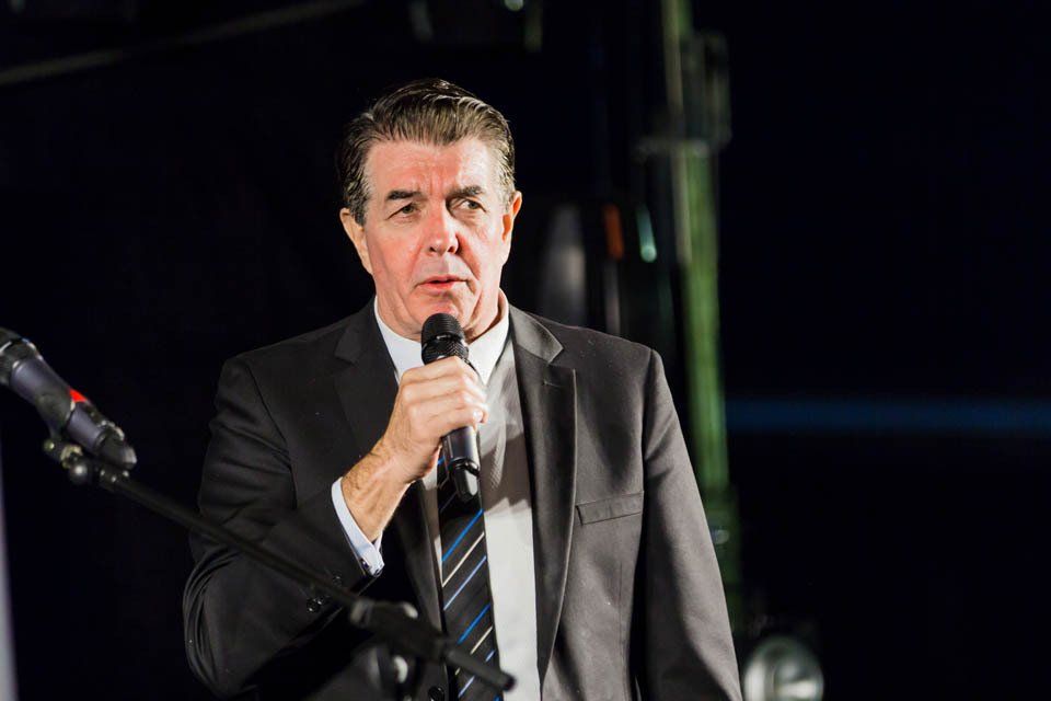 A man in a suit and tie is speaking into a microphone.