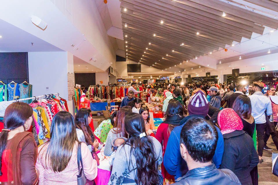 A large group of people are standing in a shopping mall.