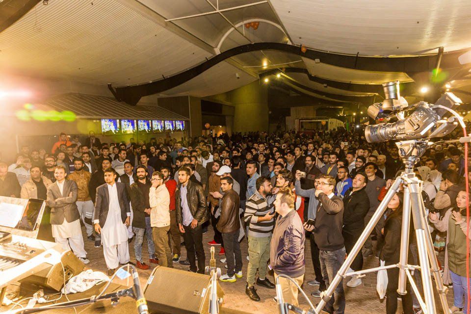 A large group of people are standing in front of a stage.