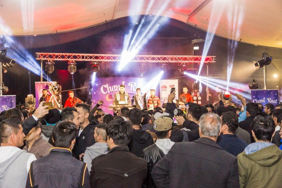 A crowd of people are standing in front of a stage at a concert.