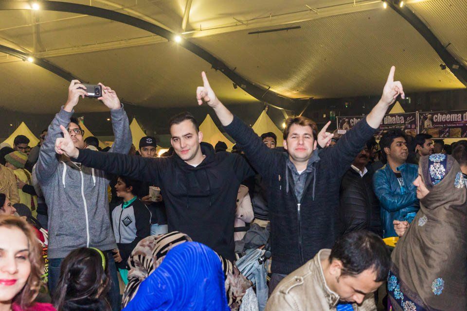 A group of people are standing in a room with their arms in the air.