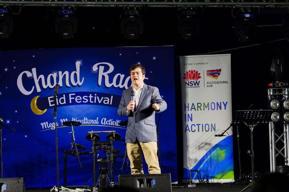 A man is standing on a stage holding a microphone.