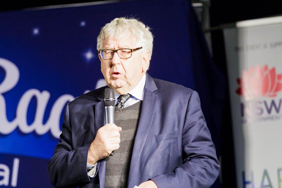 A man in a suit and tie is speaking into a microphone.