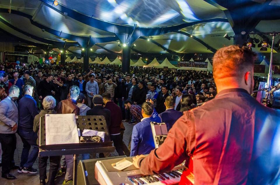 A man is playing a keyboard in front of a crowd at a concert.