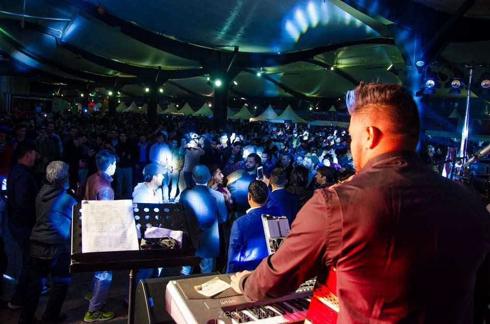 A man is playing a keyboard in front of a crowd at a concert.