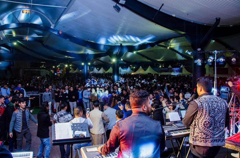 A man is playing a keyboard in front of a crowd at a concert.