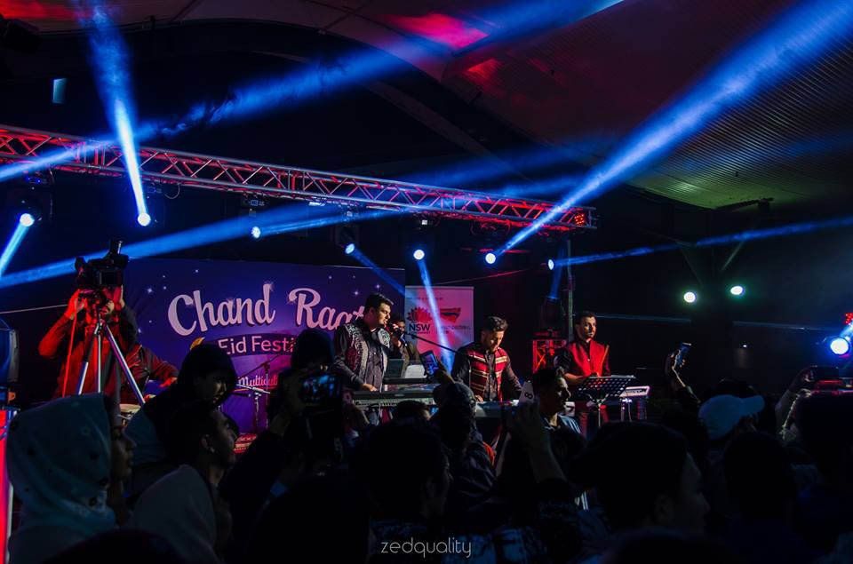 A group of people are sitting in front of a stage at a concert.