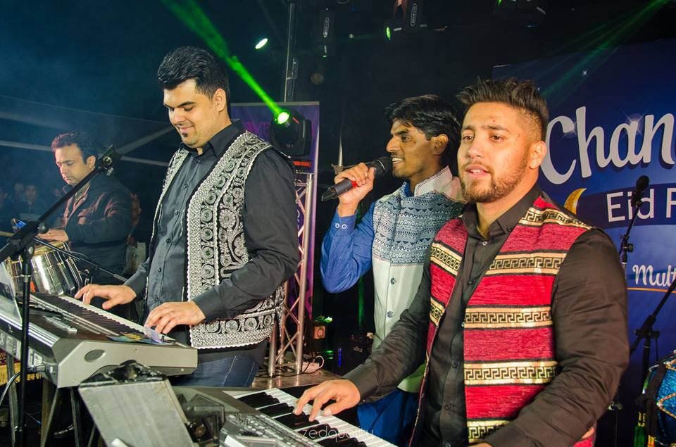 A group of men are playing keyboards and singing on stage.