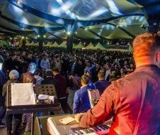 A man is playing a keyboard in front of a crowd at a concert.