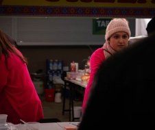 A woman in a pink hat is standing in front of a table.