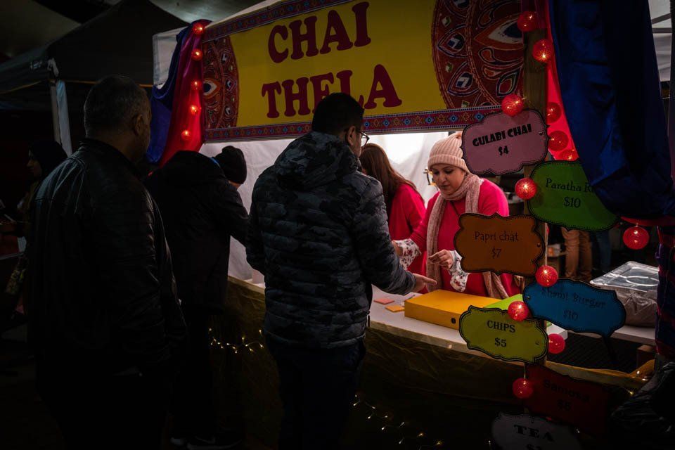 A group of people are standing around a food stand called chai thela.