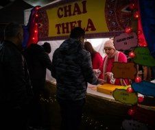 A man is standing in front of a sign that says chai thela.