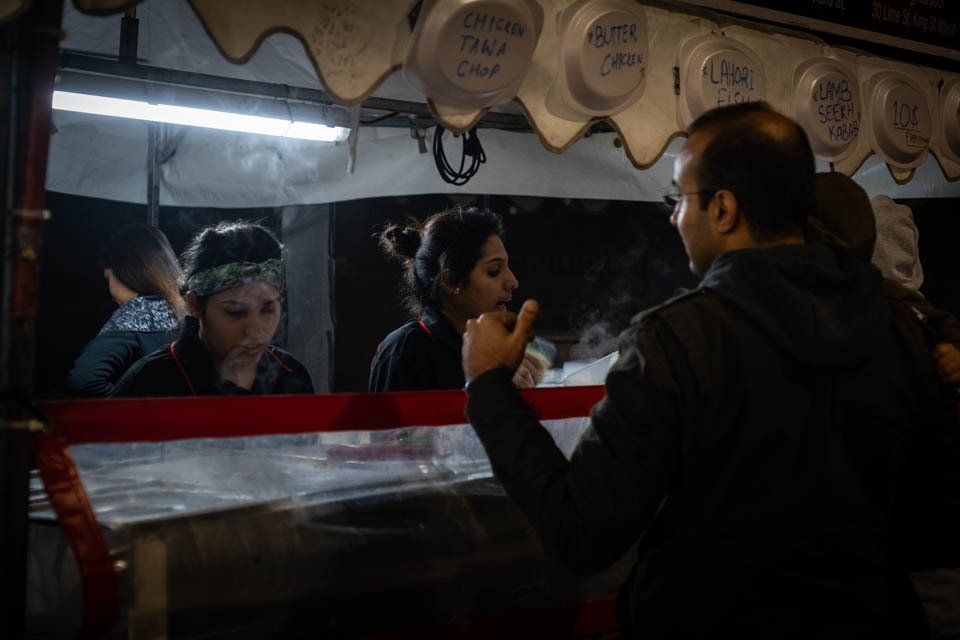 A man is talking to a woman at a food stand.