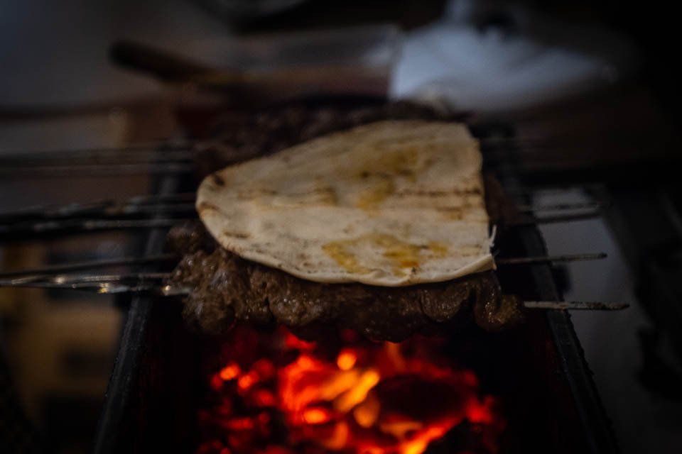 A piece of bread is sitting on top of a piece of meat on a grill.