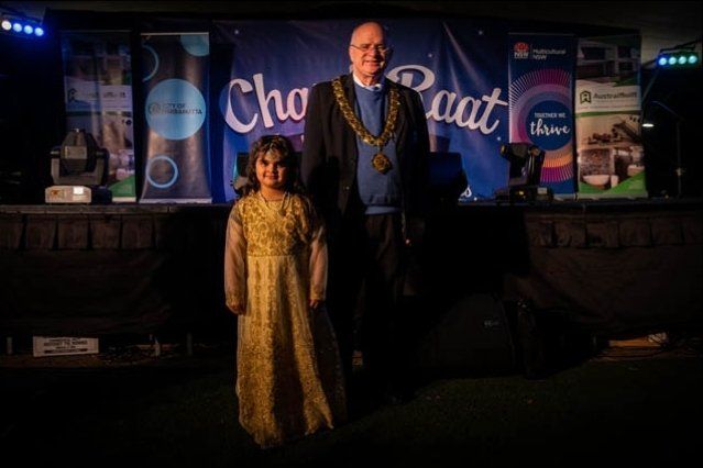 A man and a little girl are standing in front of a sign that says cho paat