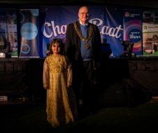 A man and a little girl are standing next to each other in front of a stage.
