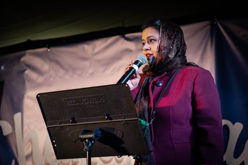A woman in a hijab is singing into a microphone