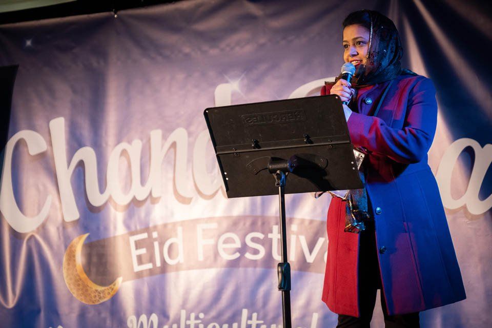 A woman is standing on a stage holding a microphone.