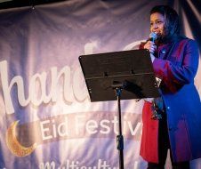 A woman is standing at a podium holding a microphone.