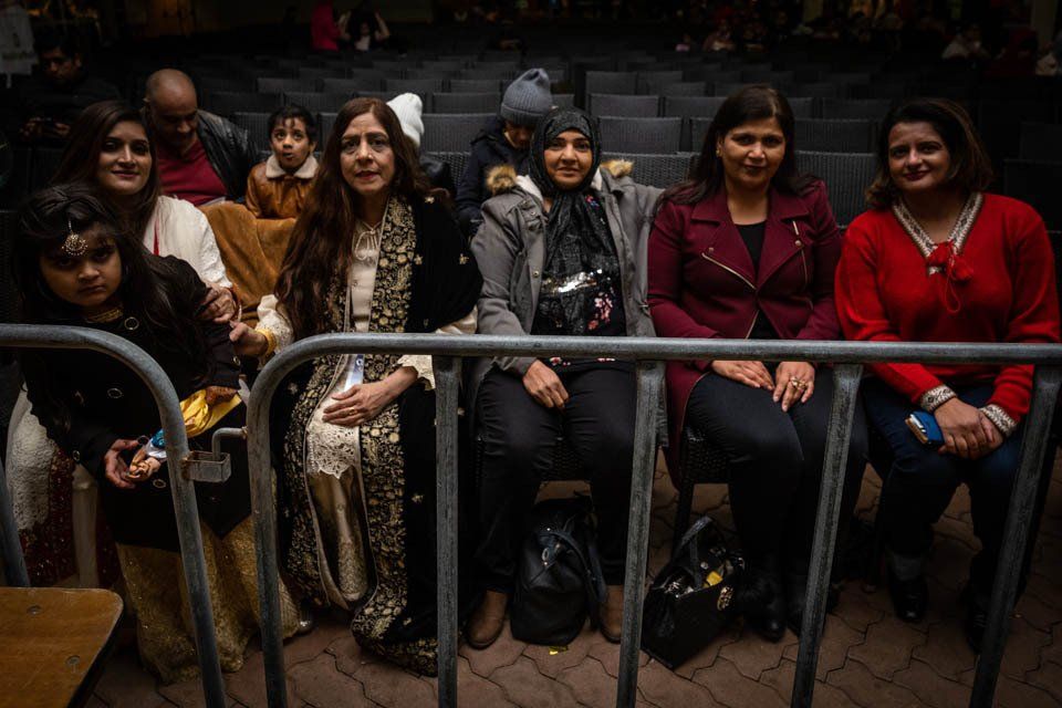 A group of women are sitting in a row behind a fence.
