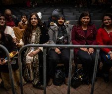A group of people are sitting in a stadium behind a fence.