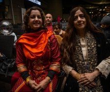 Two women are sitting next to each other in a crowded room.
