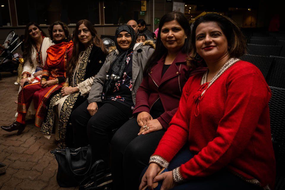A group of women are sitting next to each other on a bench.
