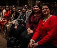 A group of women are sitting next to each other on a bench.