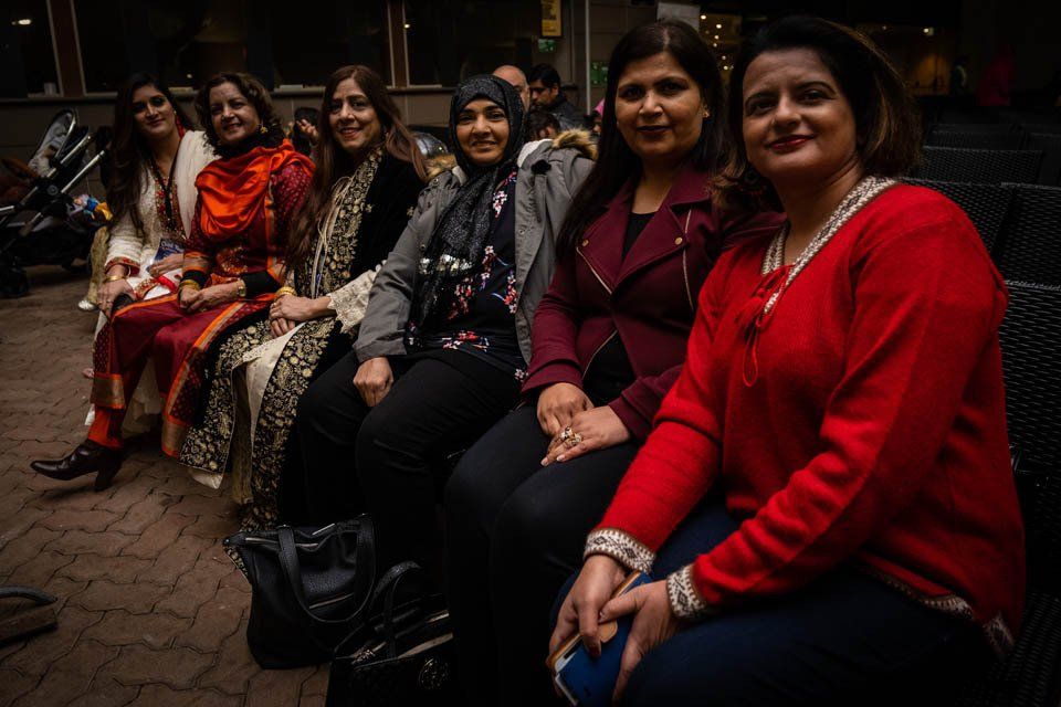 A group of women are sitting next to each other on a bench.