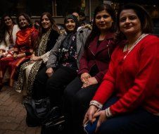 A group of women are sitting next to each other on a bench.