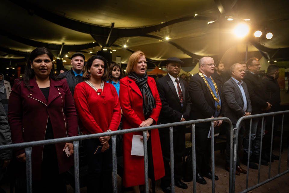 A group of people standing behind a metal fence.