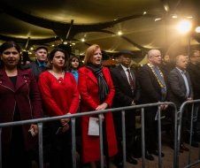 A group of people standing behind a metal fence.