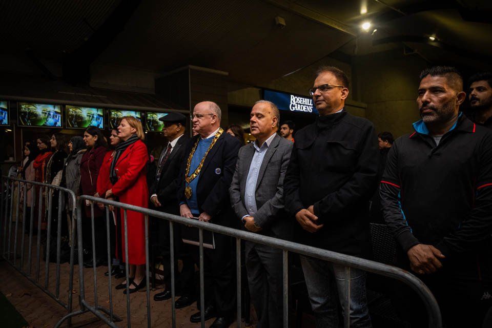 A group of people standing behind a metal fence.