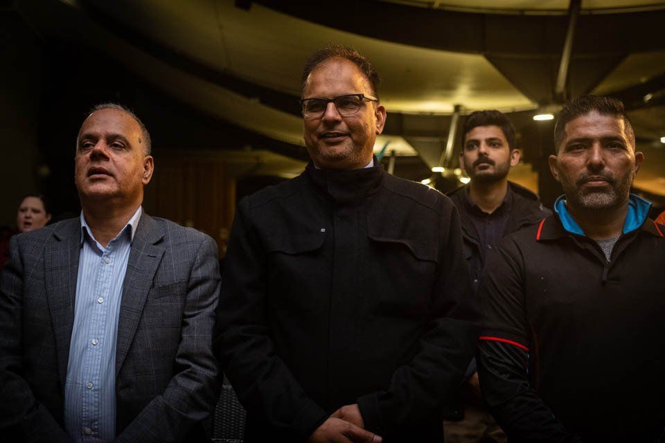 A group of men are standing next to each other in a dark room.