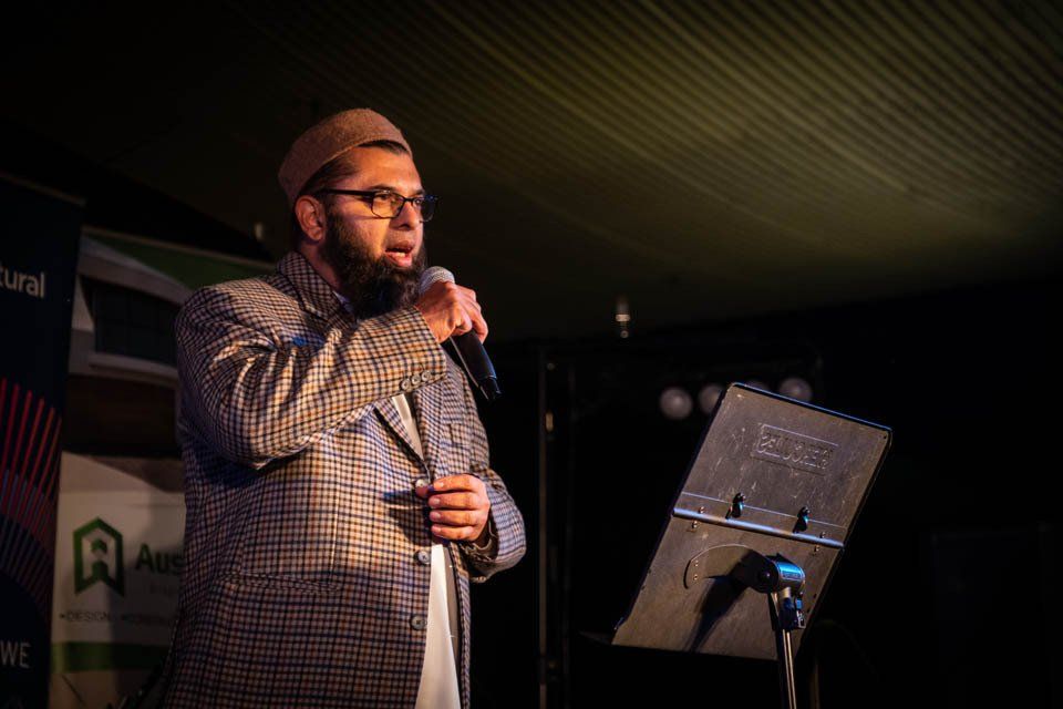 A man with a beard is standing in front of a microphone.