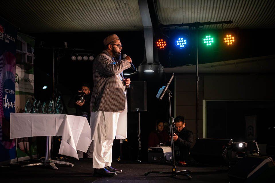 A man is standing on a stage holding a microphone.