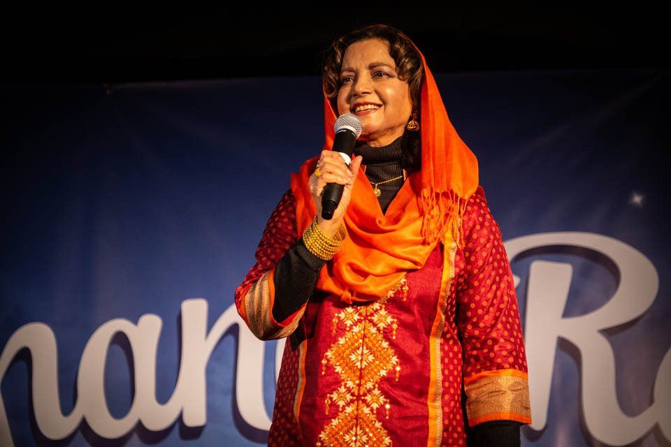 A woman in a red and orange dress is holding a microphone.