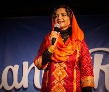 A woman in a red dress is holding a microphone and smiling.