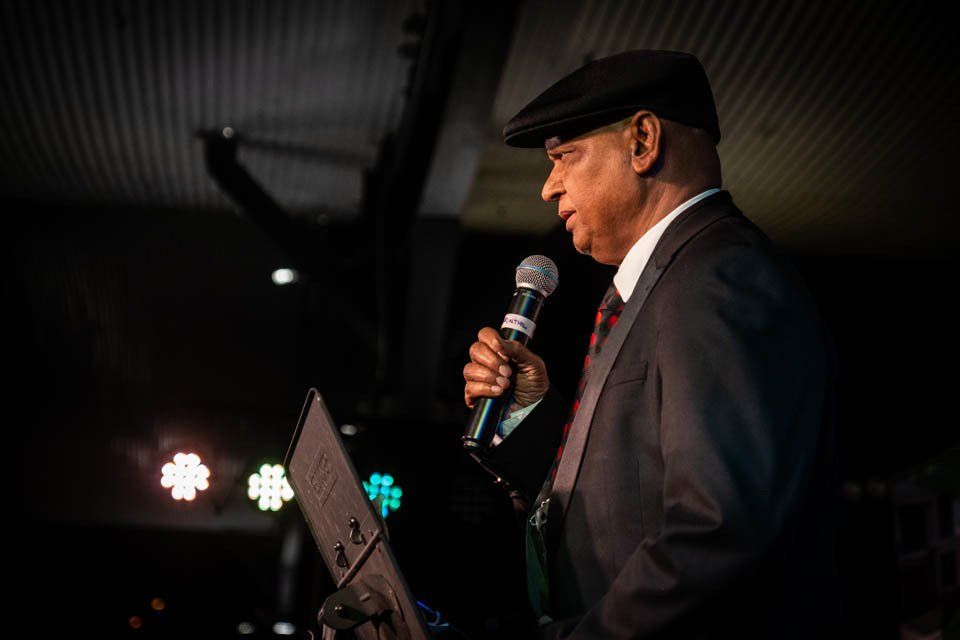 A man in a suit and hat is singing into a microphone.