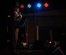 A man is standing on a stage holding a microphone.