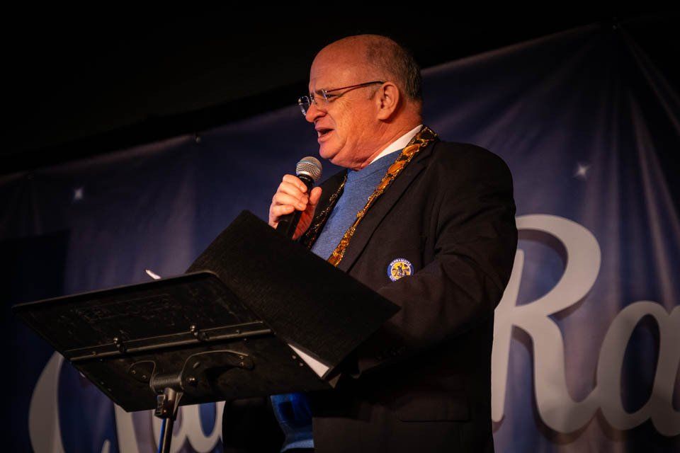A man is standing at a podium speaking into a microphone.