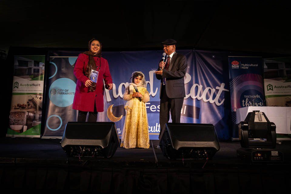 A little girl is standing on a stage with a man and a woman.