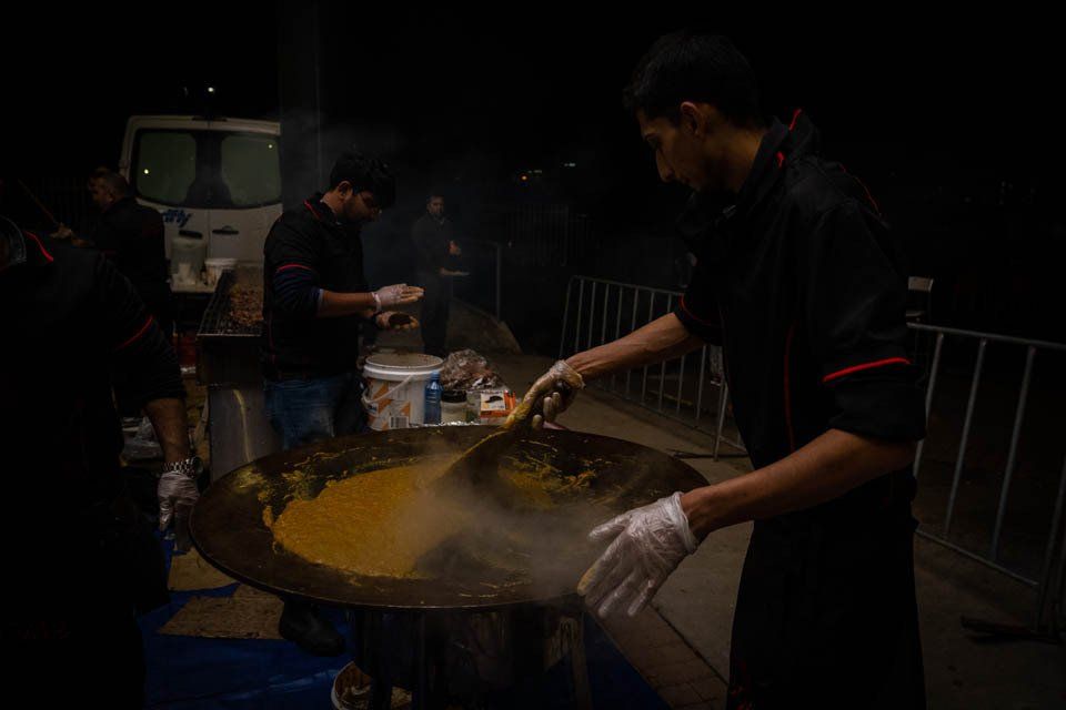 A man is cooking food in a large pot at night.