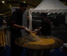 A man is cooking food on a grill in a dark room.