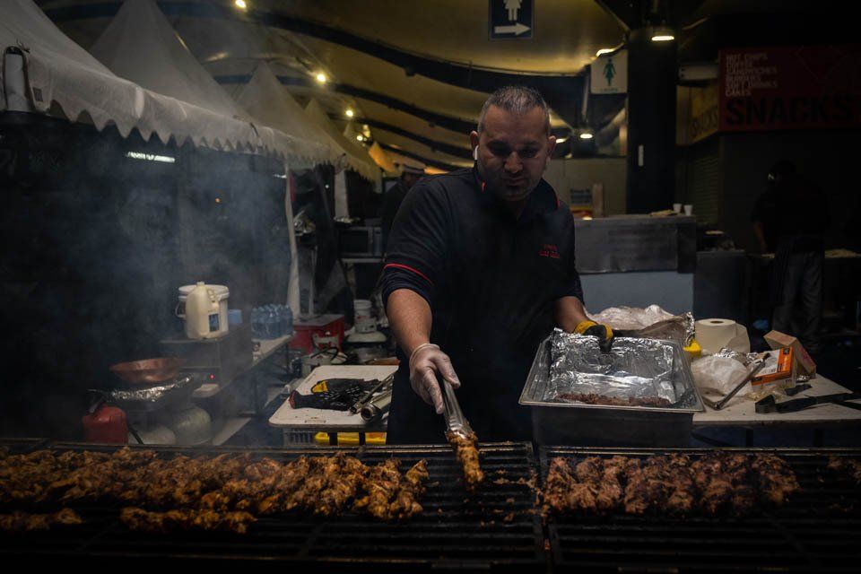 A man is cooking meat on a grill in a restaurant.