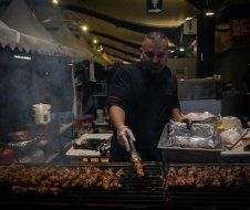 A man is cooking meat on a grill in a restaurant.