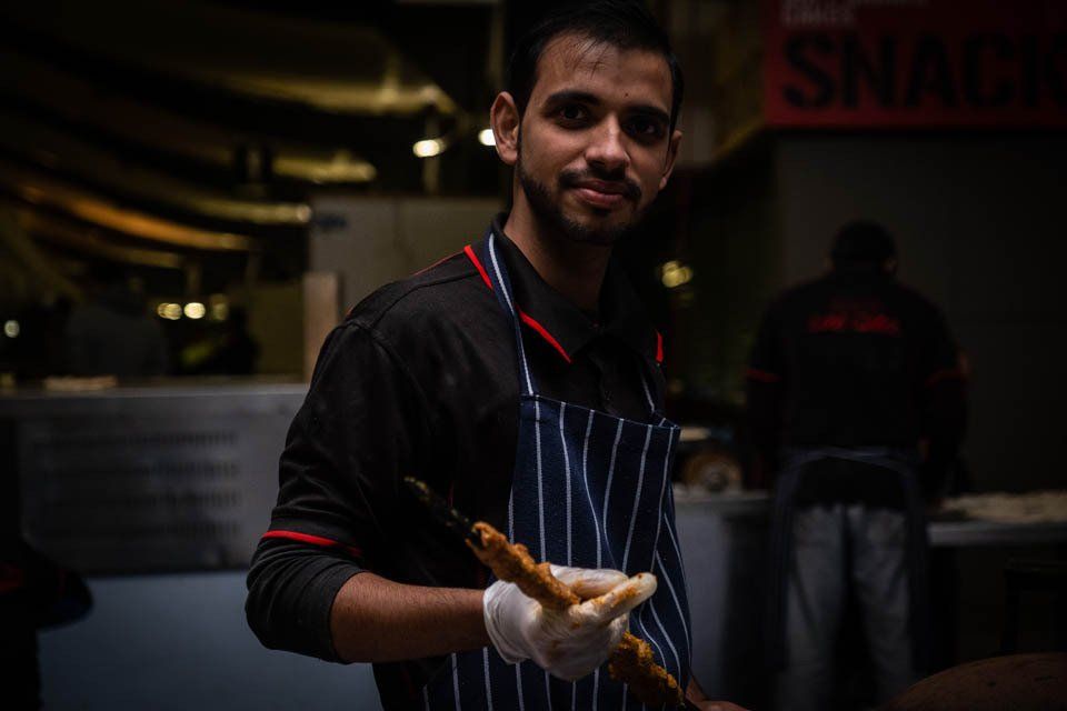 A man in an apron is holding a piece of bread in his hand.