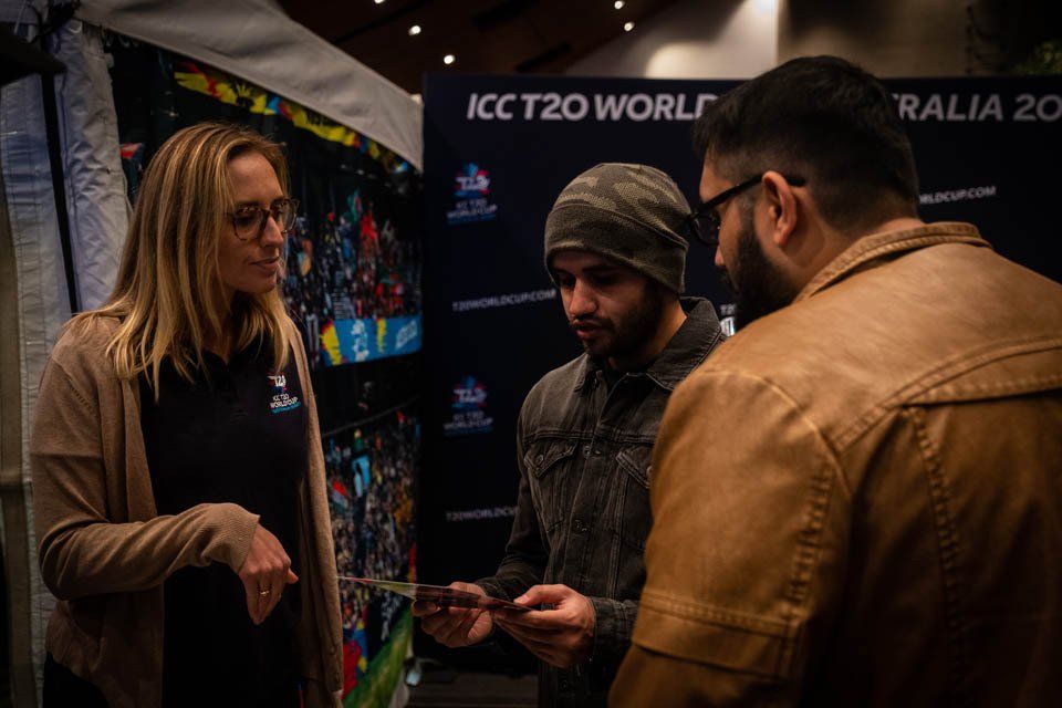 A group of people are standing around a table talking to each other.