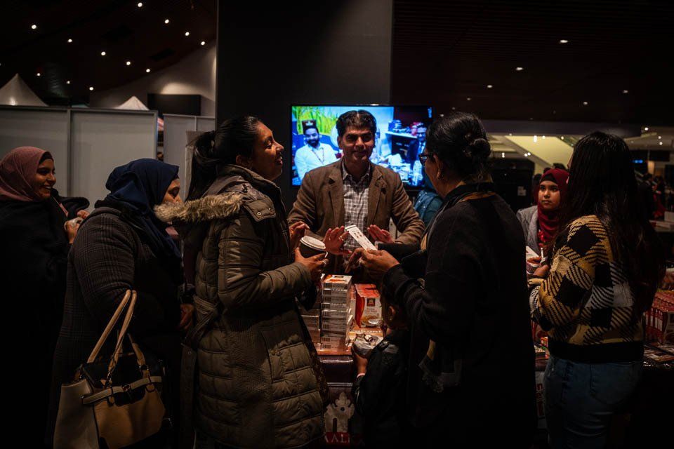 A group of people are standing in a dark room talking to each other.